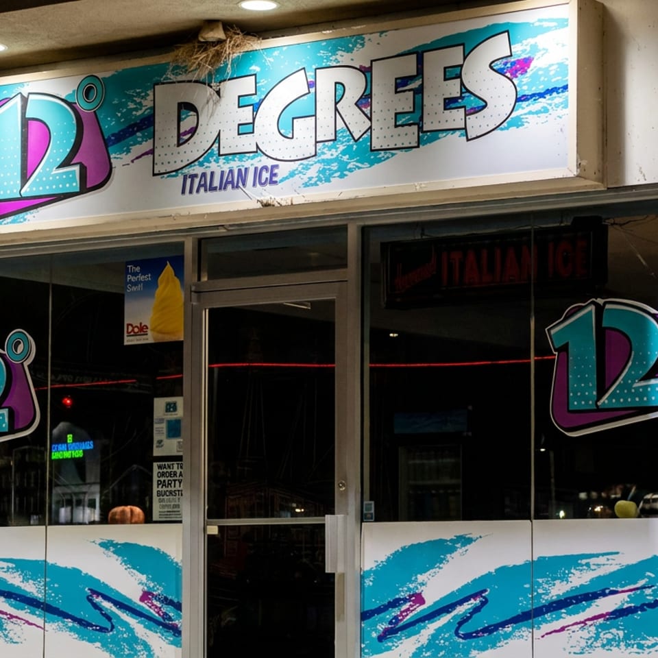 Exterior storefront of 12 Degrees Italian Ice, featuring colorful logos, glass doors, and turquoise-purple wave graphics.